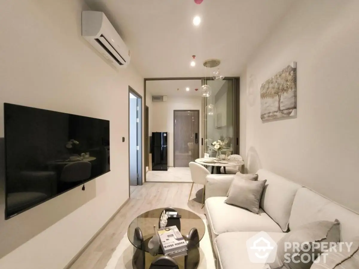 Modern living room with sleek design and neutral tones, featuring a wall-mounted TV and stylish furniture.