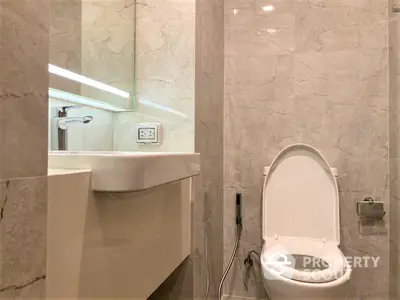 Modern bathroom with elegant marble tiles, sleek fixtures, and well-placed lighting creating a luxurious and serene atmosphere.