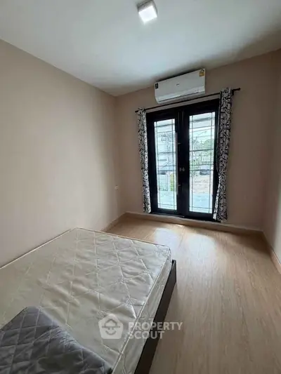Cozy bedroom with balcony access and air conditioning in modern apartment.