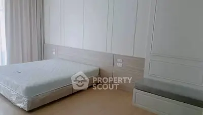 Spacious bedroom with modern design and natural light, featuring a comfortable bed and elegant wall paneling.
