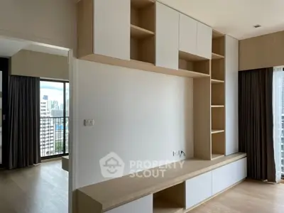 Modern living room with built-in wooden shelves and city view balcony.