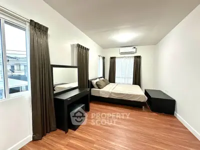Spacious bedroom with modern furnishings and large windows for natural light.