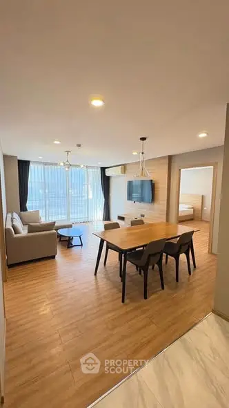 Spacious modern living room with open dining area and large windows.