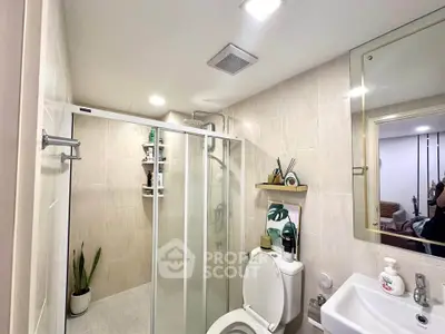 Modern bathroom with glass shower, sleek fixtures, and elegant decor.