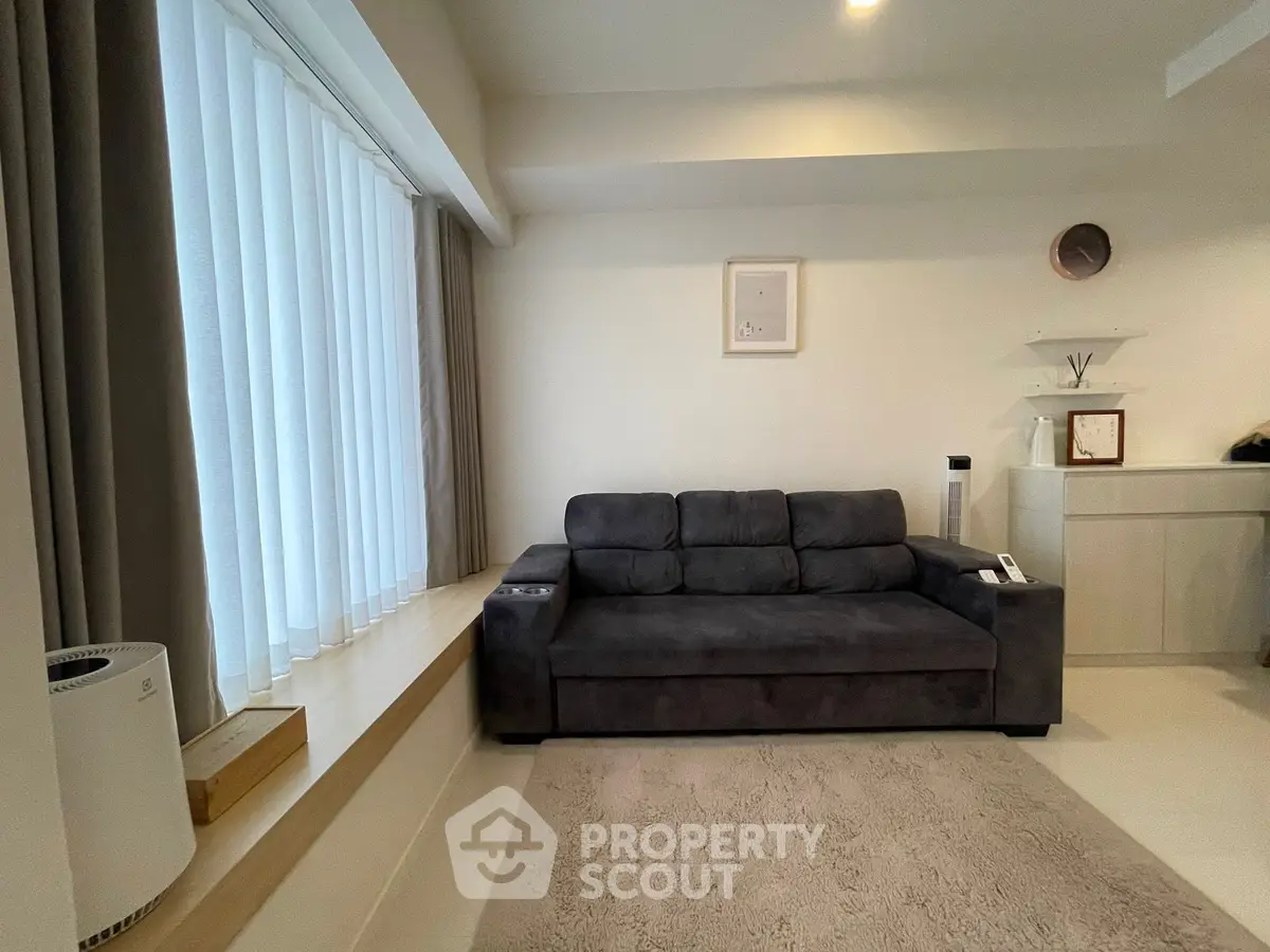 Modern living room with sleek gray sofa and large window, offering a cozy and inviting atmosphere.