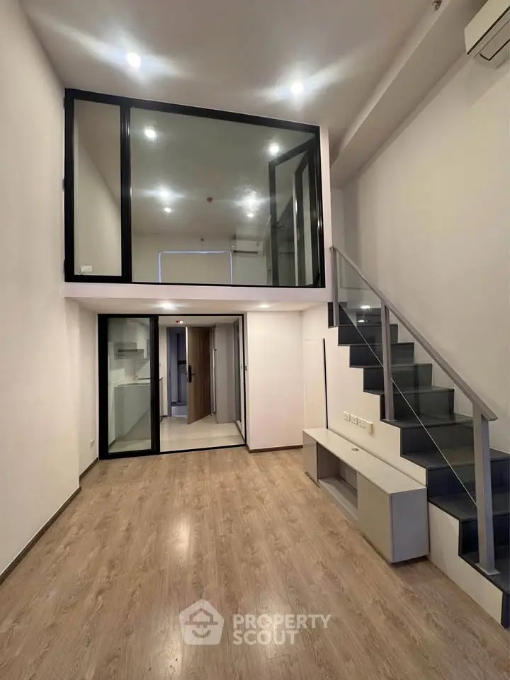 Modern duplex apartment with mezzanine and sleek staircase in open living area.