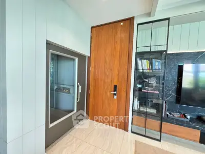 Modern living room with sleek elevator and wooden door, featuring stylish shelving and marble accents.