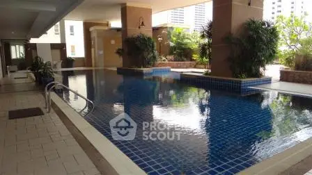 Luxurious condominium pool area with modern design and lush greenery, perfect for relaxation and leisure.