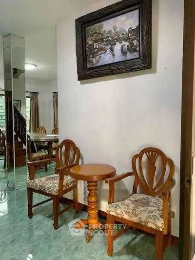 Charming interior with elegant wooden chairs and a framed painting, perfect for cozy living spaces.