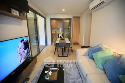 Modern living room with open kitchen, stylish decor, and cozy seating area.