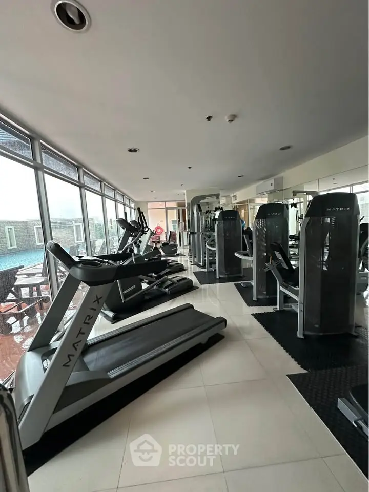 Modern gym with state-of-the-art equipment and large windows offering a bright and inviting workout space.