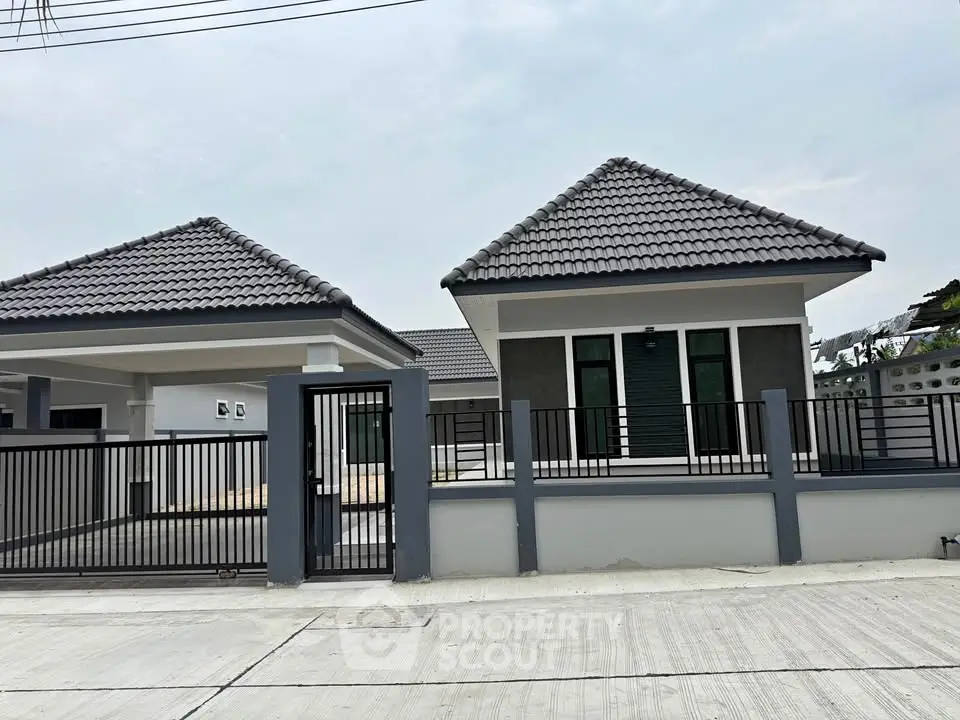 Modern single-story house with tiled roof and gated entrance, showcasing contemporary architecture.