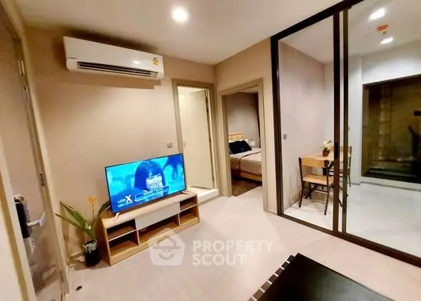 Modern living room with TV and air conditioning, adjacent to bedroom and dining area.