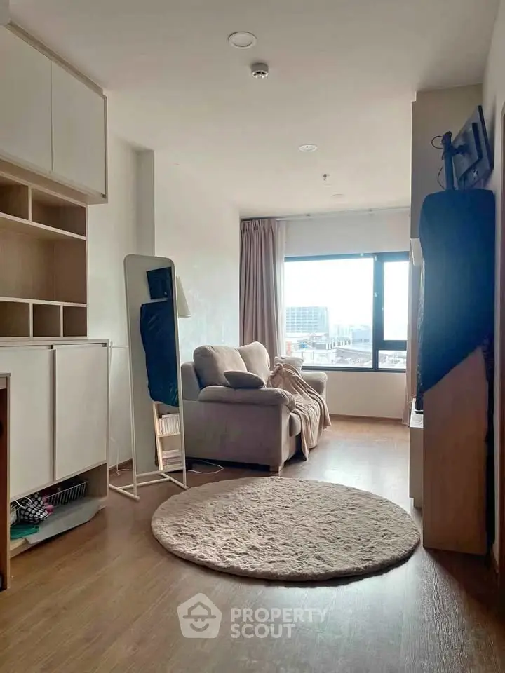 Cozy living room with large window and modern furnishings, offering a bright and inviting atmosphere.