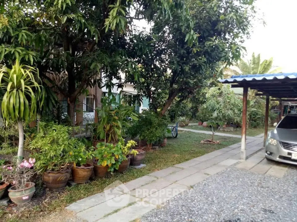 Charming garden view with lush greenery and carport in a serene residential setting.