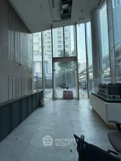 Spacious modern building entrance with floor-to-ceiling windows and urban view.