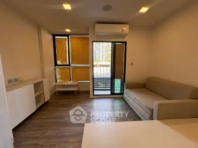 Modern living room with balcony access and air conditioning, featuring sleek furniture and natural light.