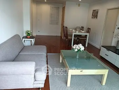Spacious living room with elegant decor and dining area, featuring a cozy sofa and glass coffee table.