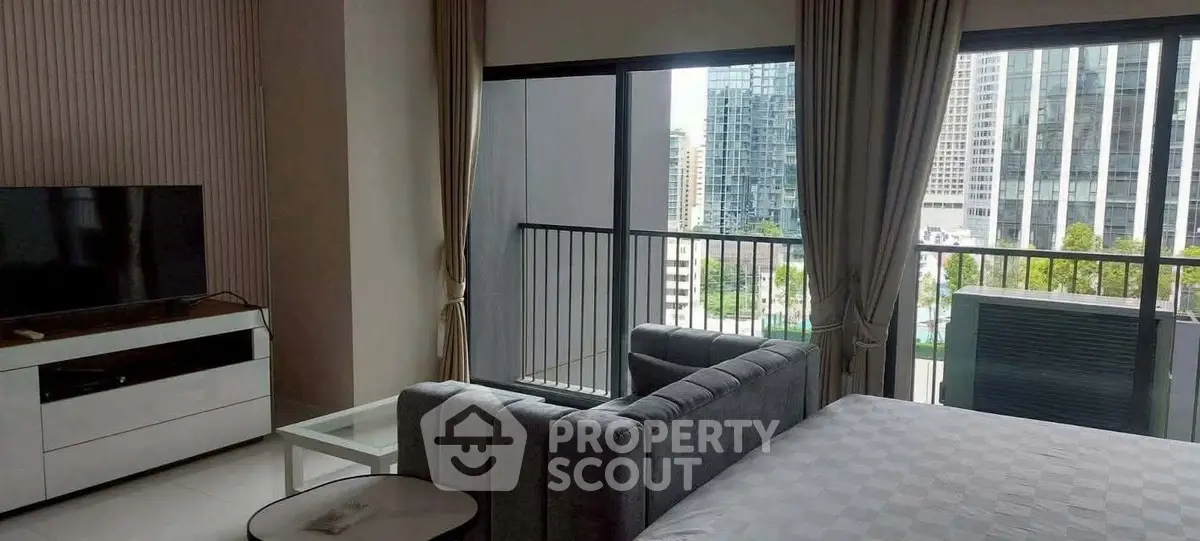 Modern apartment with balcony and city view, featuring stylish furniture and large windows.