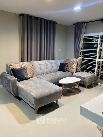 Modern living room with stylish grey sectional sofa and elegant curtains