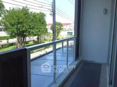 Spacious balcony with clear glass railing and scenic view of lush greenery.