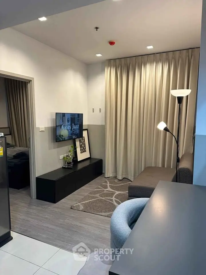 Modern living room with cozy decor and stylish lighting, featuring a wall-mounted TV and elegant curtains.