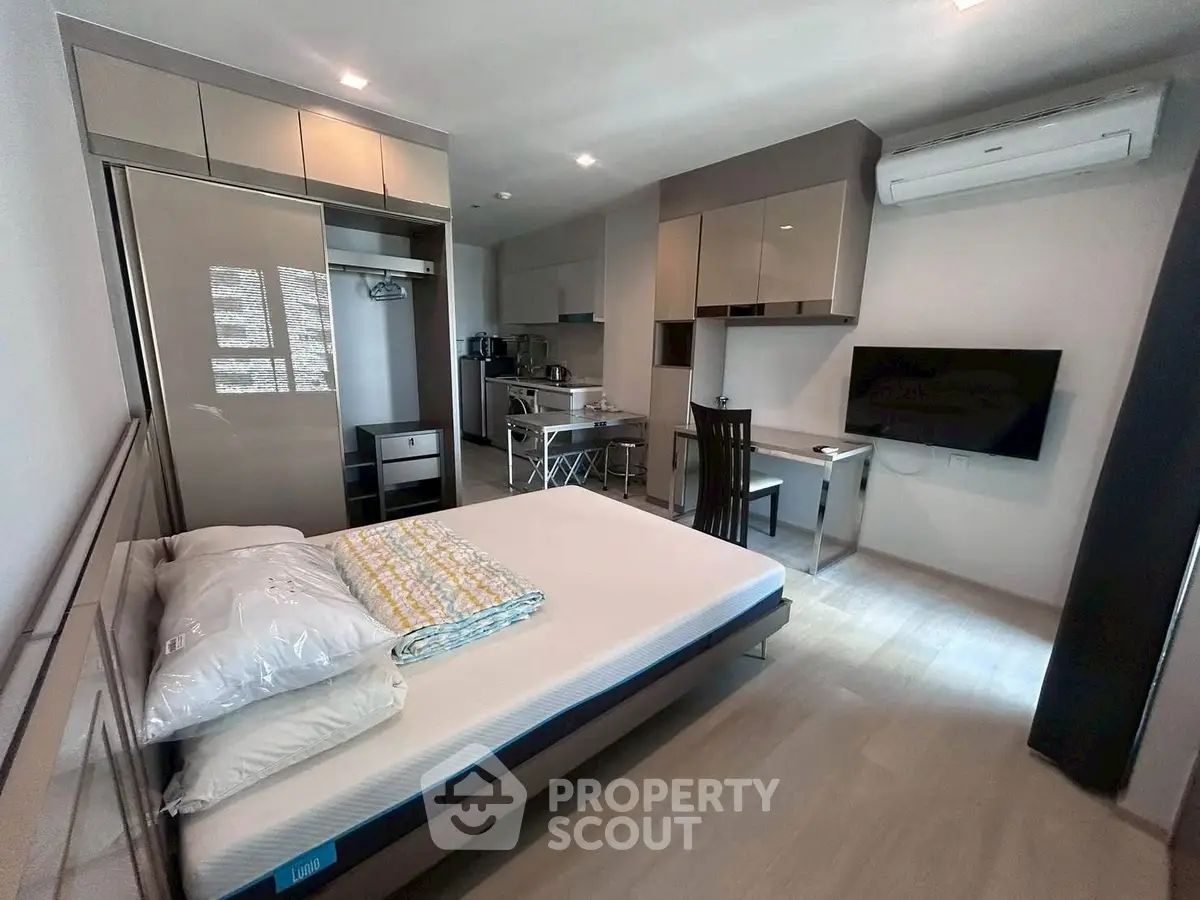 Modern studio apartment with sleek furniture and integrated kitchen area