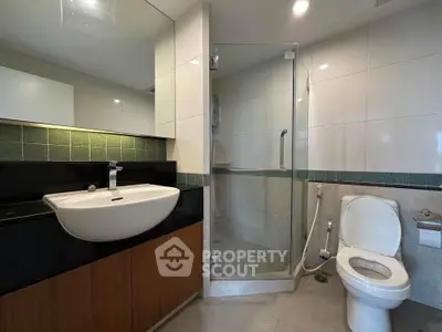 Modern bathroom with glass shower and sleek vanity in contemporary apartment.