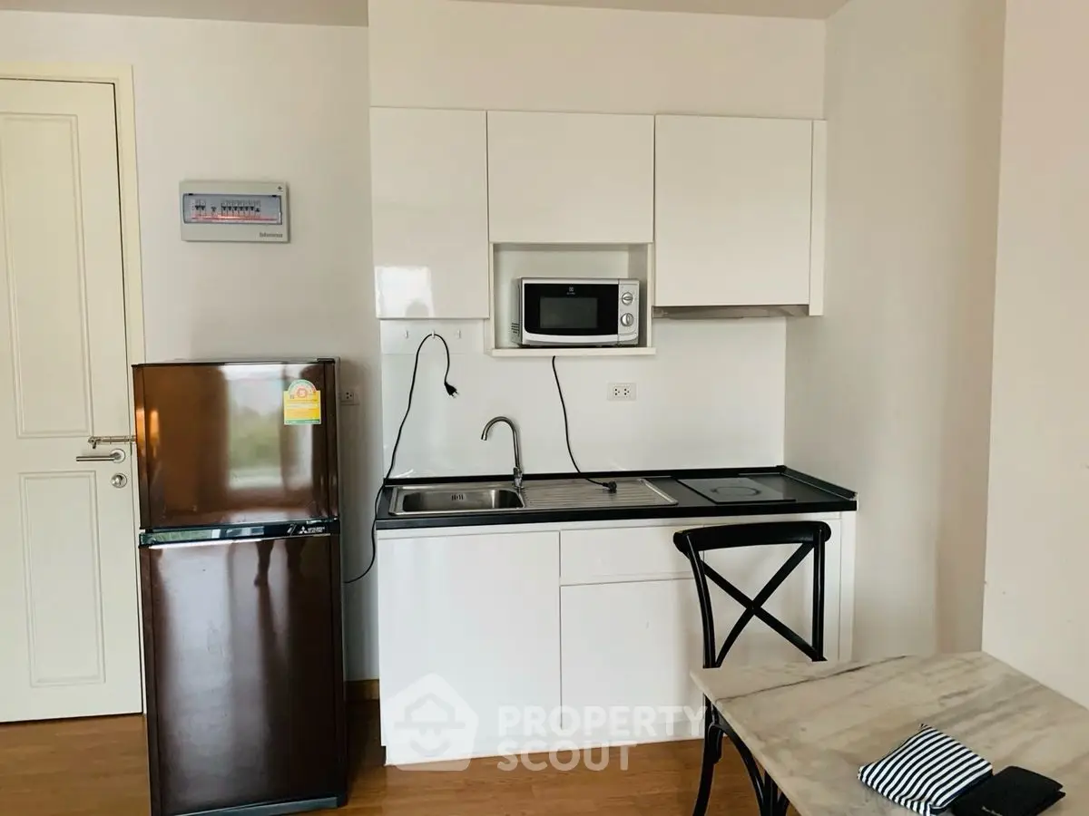 Compact kitchen with modern appliances and dining area in cozy apartment.