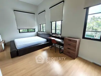 Spacious bedroom with large windows and modern furnishings in a serene setting.