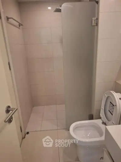 Modern bathroom with sleek shower and toilet in minimalist design.