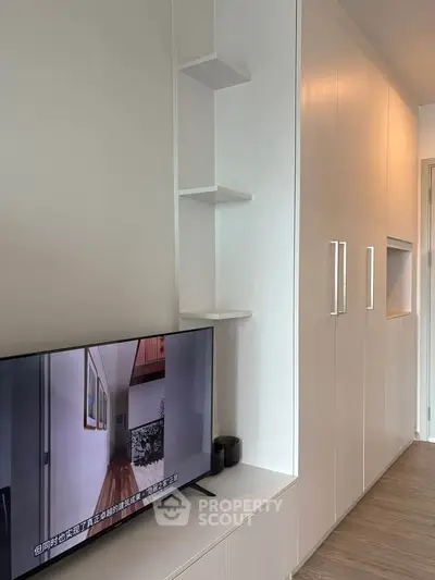 Modern living room with sleek built-in storage and flat-screen TV, showcasing minimalist design.