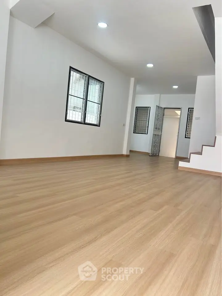 Spacious open-plan living area with wooden flooring and ample natural light.