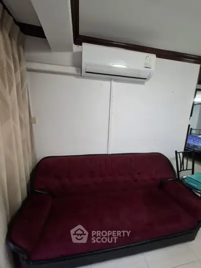 Cozy living room with plush red sofa and modern air conditioning unit, perfect for relaxation.