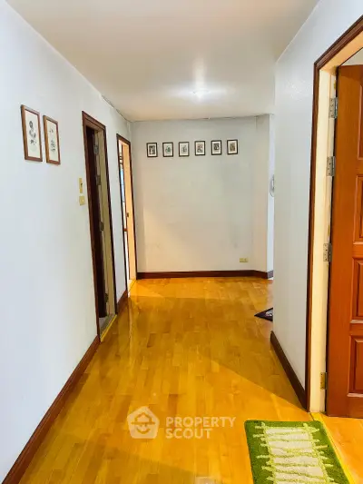 Spacious hallway with wooden flooring and framed wall art in a modern home.
