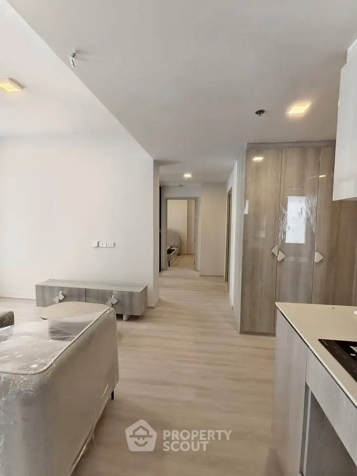 Modern open-plan living area with sleek kitchen and hallway leading to bedrooms.