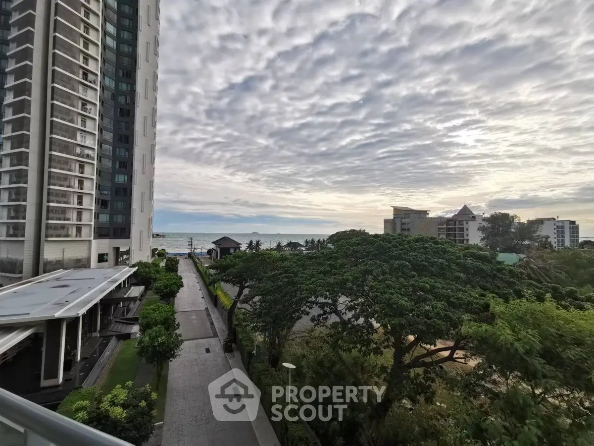 Stunning coastal view from high-rise building with lush greenery and ocean horizon.