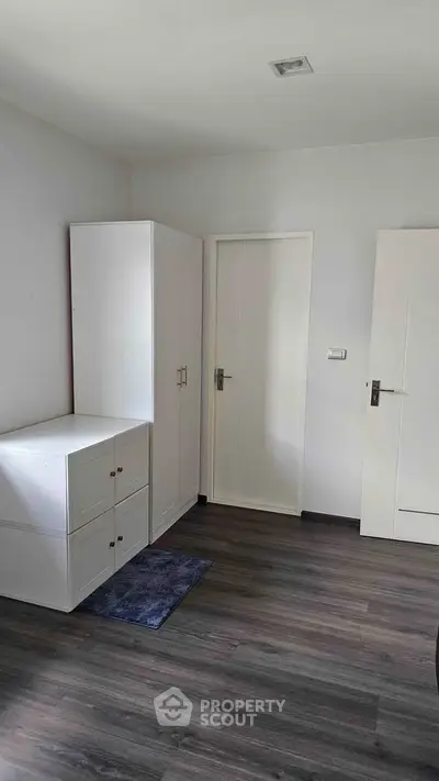 Minimalist bedroom with white furniture and wooden flooring