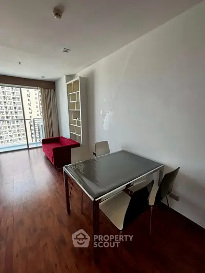 Modern living room with wooden flooring and balcony view in urban apartment.