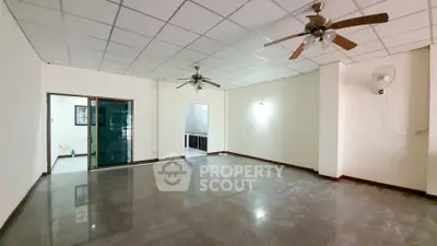 Spacious living room with ceiling fans and tiled floor, ideal for family gatherings.