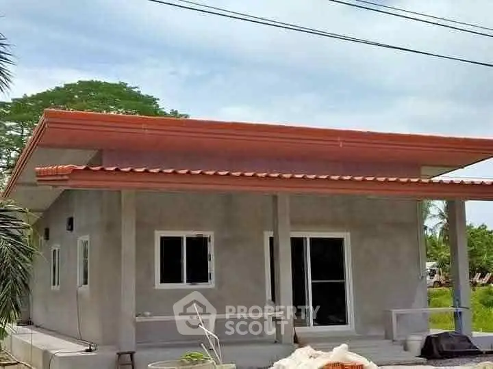 Modern single-story house with flat roof and spacious porch in a serene neighborhood.