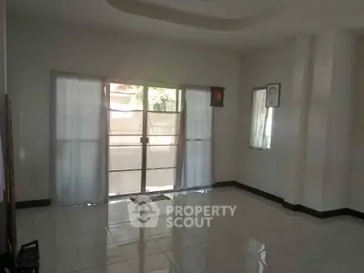 Spacious living room with large windows and tiled flooring