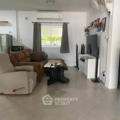 Spacious living room with modern furniture and large TV, perfect for relaxation and entertainment.