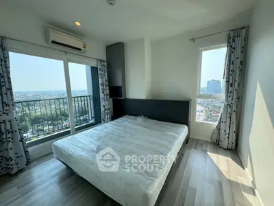 Bright bedroom with large windows and balcony offering stunning city views