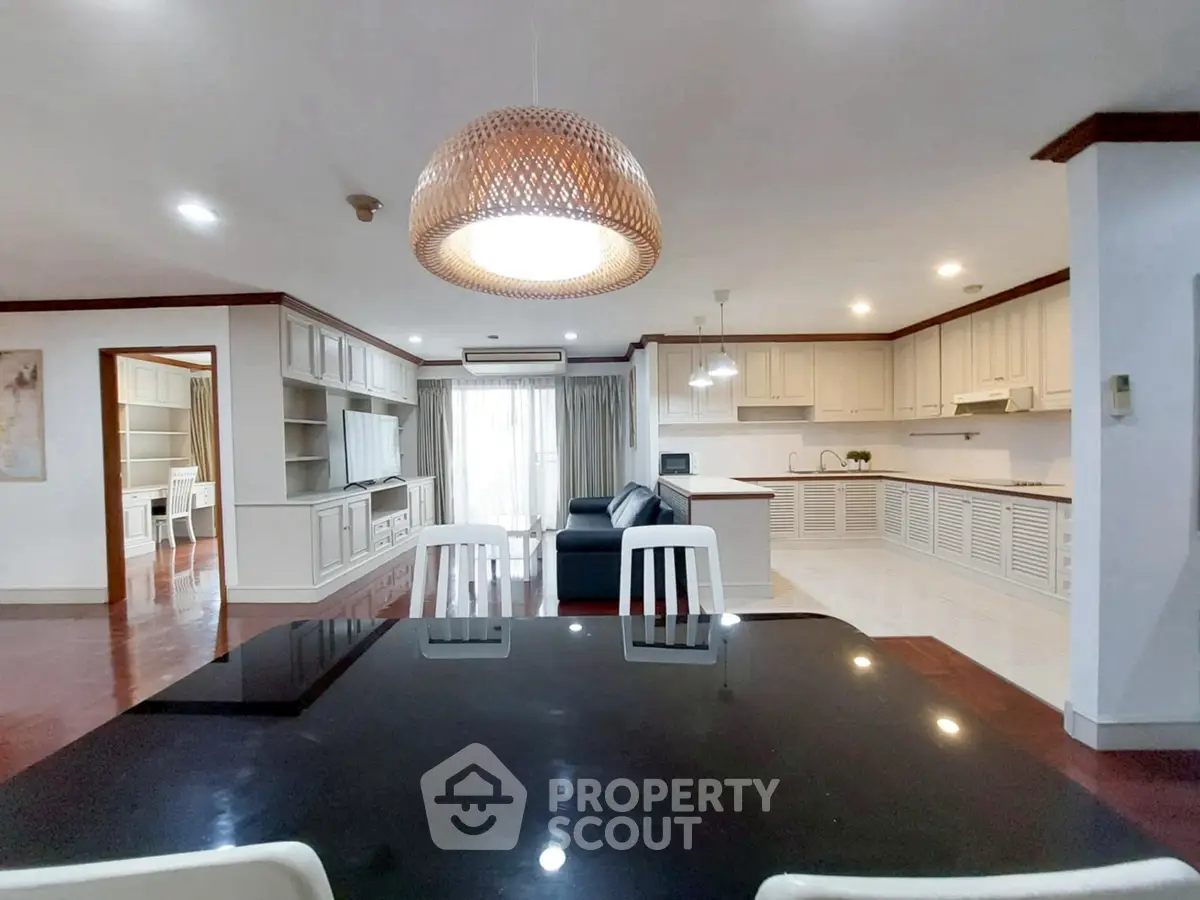 Spacious open-plan living and dining area with modern kitchen and elegant lighting.