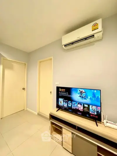 Modern living room with air conditioning and entertainment setup, featuring a sleek TV and minimalist furniture.