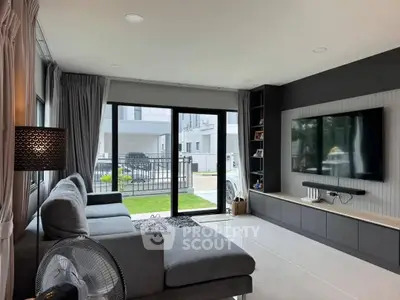 Modern living room with sleek design, large TV, and spacious sofa overlooking a garden view.