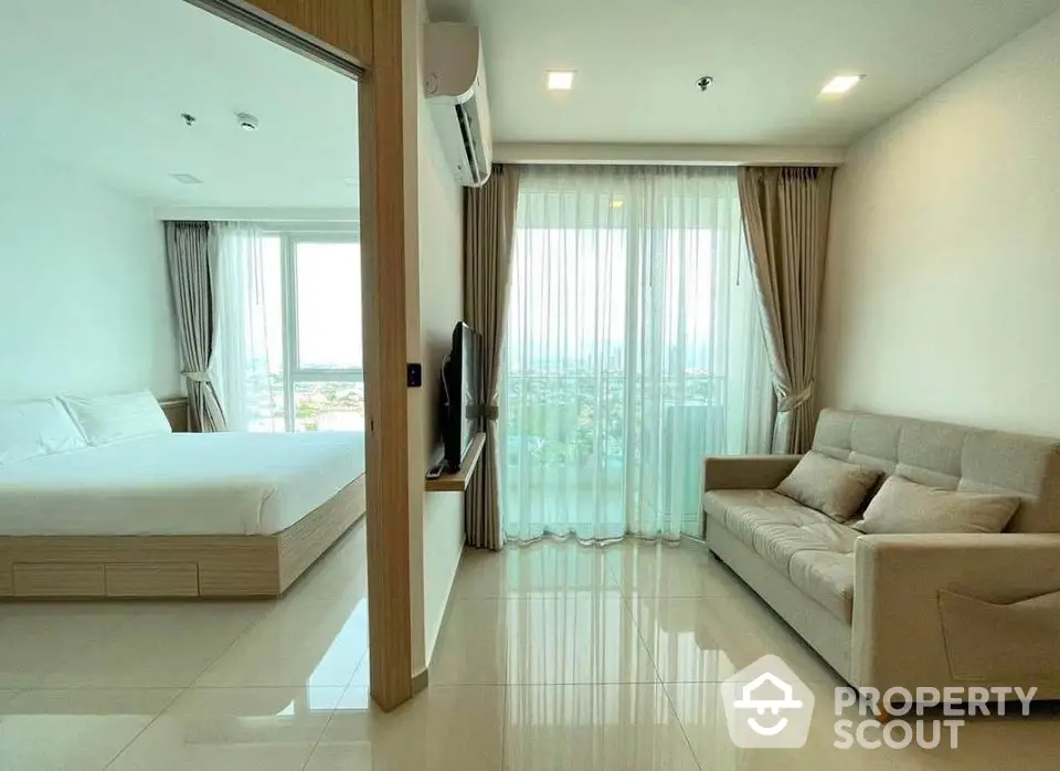 Modern apartment with spacious living room and bedroom, featuring large windows and natural light.