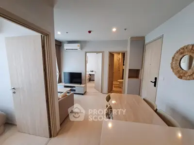 Modern open-plan living room with dining area and TV, featuring neutral tones and stylish decor.