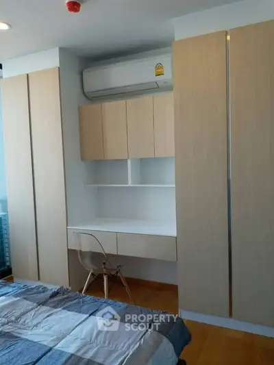Modern bedroom with built-in wardrobe and study desk, featuring sleek design and ample storage space.